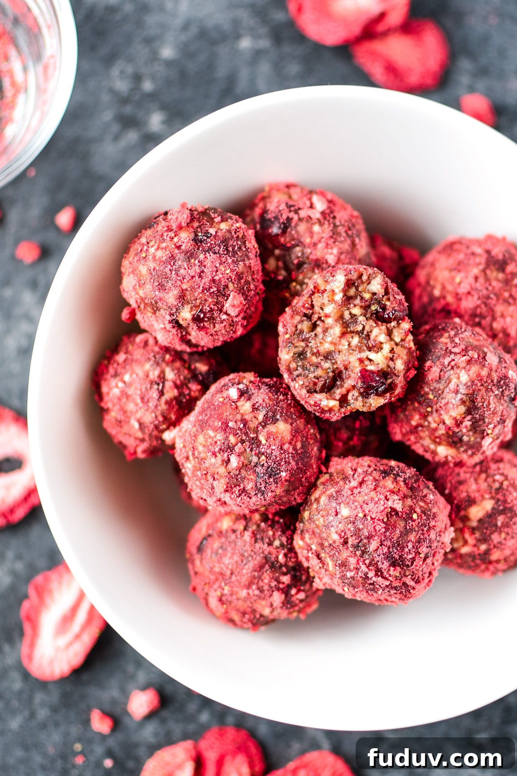 Spiced Berry Energy Balls: No-Bake Snack Recipe 6 A white bowl of Spiced Berry Bliss Balls with a bite taken out of one.