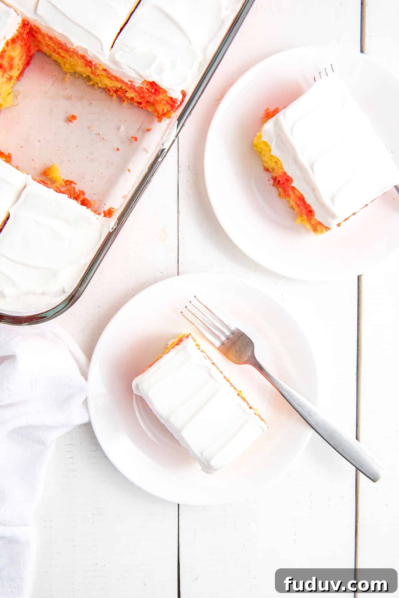 Overhead view of poke cake squares on plates with the baking dish next to the plates.
