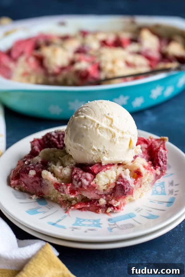 Strawberry dump cake on a plate with a scoop of vanilla ice cream on top 