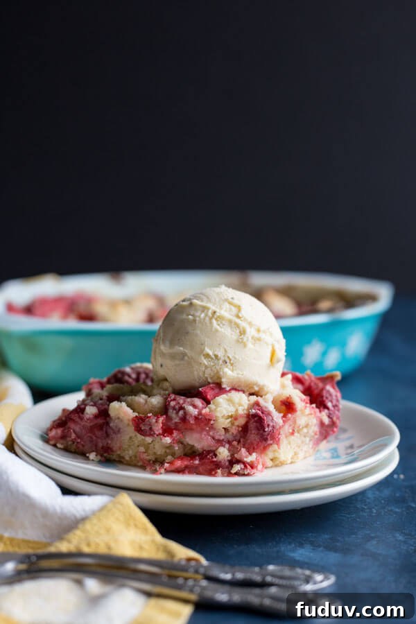 Strawberry dump cake on a plate with a scoop of vanilla ice cream on top 