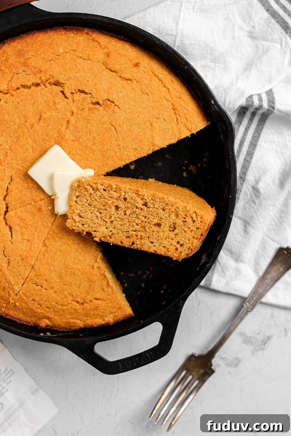Sweet Potato Cornbread Recipe with Maple Butter Glaze 5 slice of sweet potato cornbread with butter in a cast iron skillet