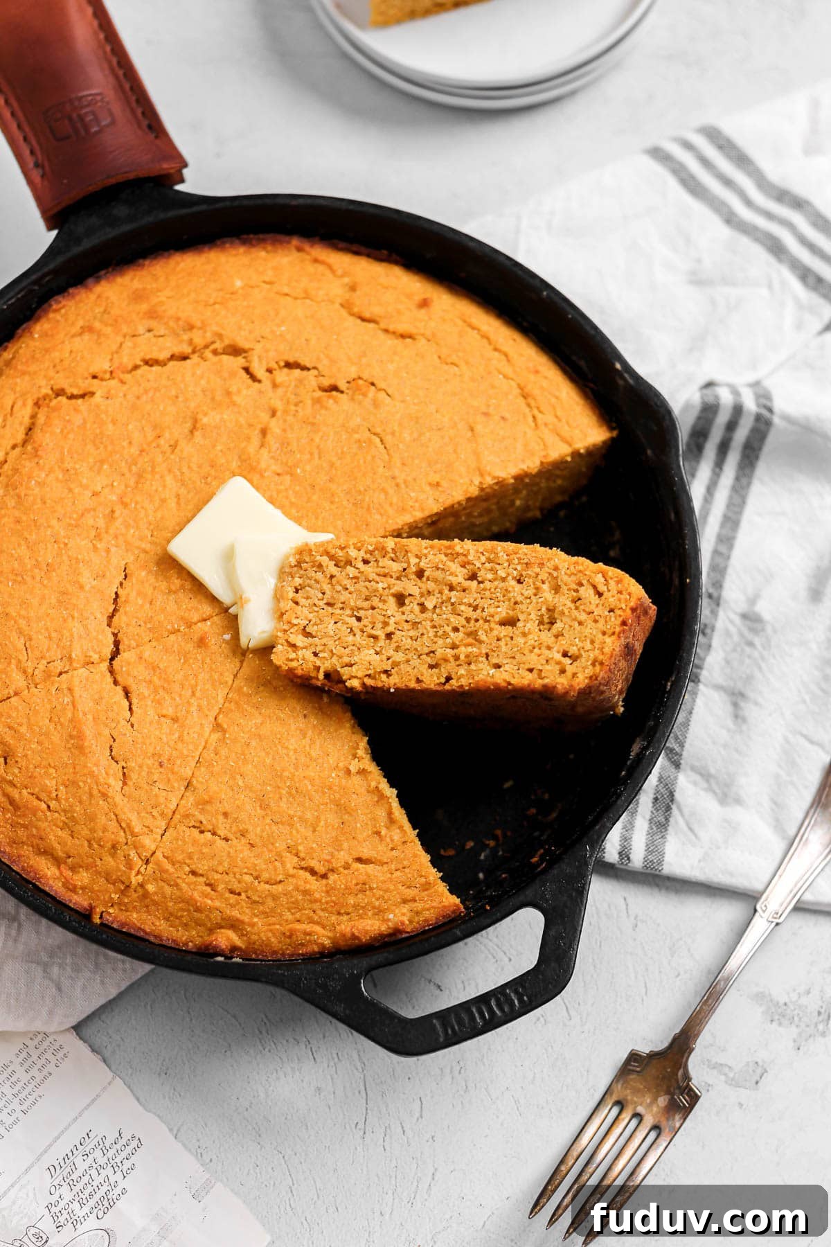 Sweet Potato Cornbread Recipe with Maple Butter Glaze 7 slice of sweet potato cornbread with butter in a cast iron skillet
