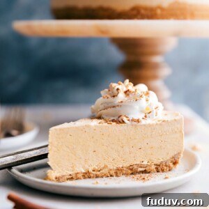 No-Bake Pumpkin Cheesecake Recipe — Creamy Fall Dessert 4 A tempting slice of no-bake pumpkin cheesecake with the whole cheesecake in the background, ready to be savored.