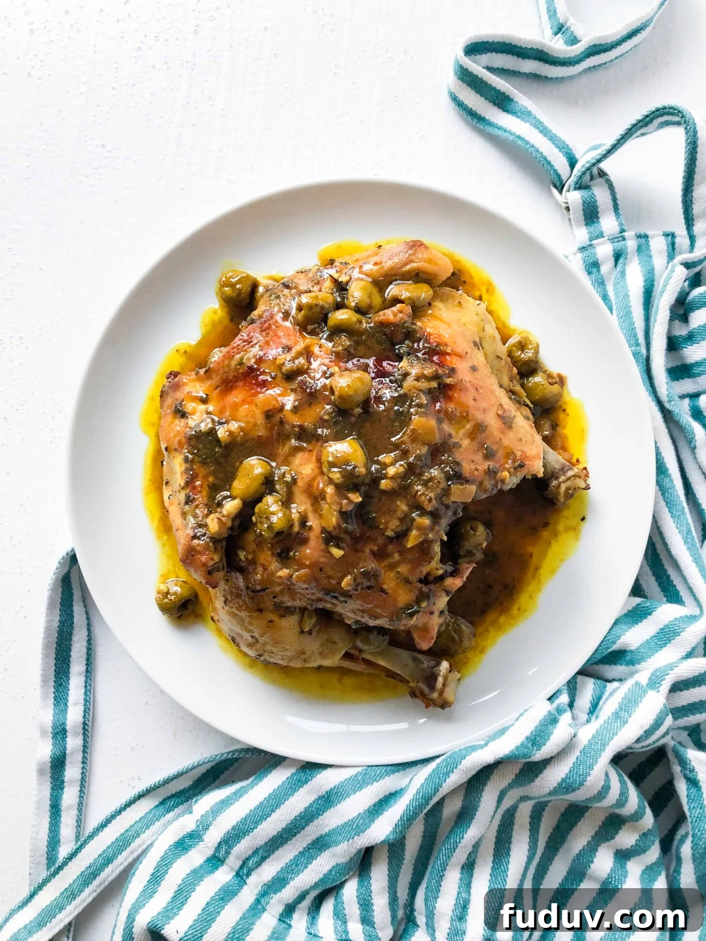 Moroccan Preserved Lemon Chicken with Olives Recipe 2 Moroccan chicken with olives on a plate with a striped towel