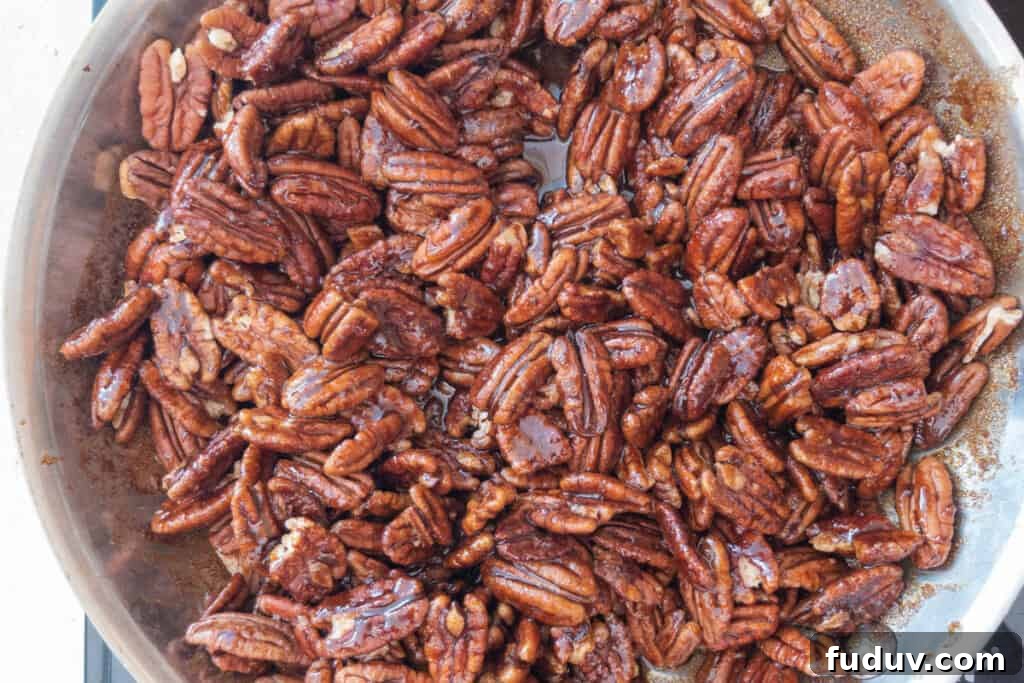 Quick Candied Pecans Recipe: Sweet Glazed Pecans in 20 Minutes 9 cooking homemade candied pecans in a skillet.