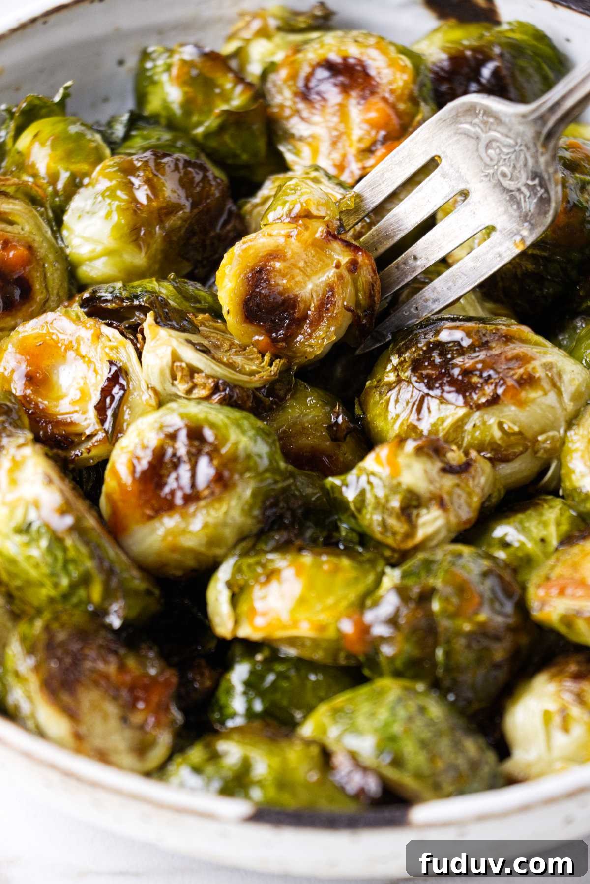 Honey Sriracha Roasted Brussels Sprouts 7 A fork in a dish with sriracha brussel sprouts.