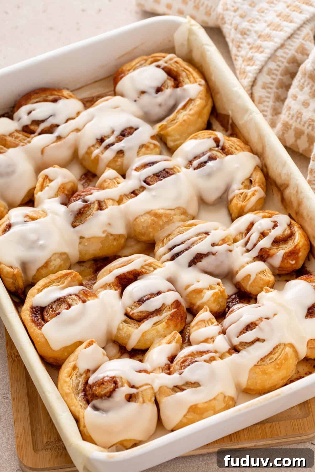 White baking pan filled with glazed puff pastry cinnamon rolls.