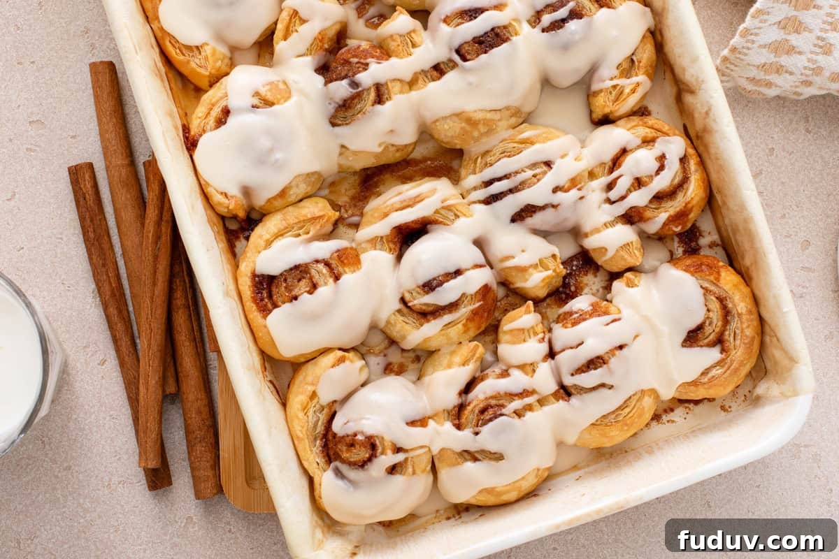 Overhead view of puff pastry cinnamon rolls in a white baking pan.