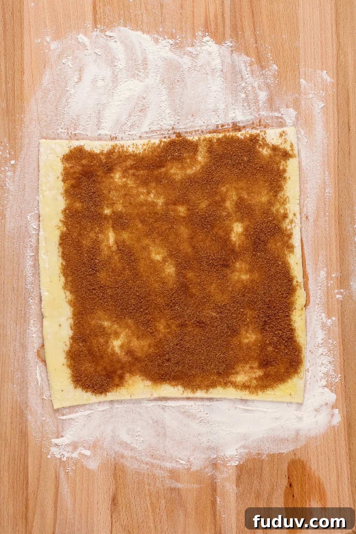 Sheet of puff pastry topped with melted butter and cinnamon-sugar filling.