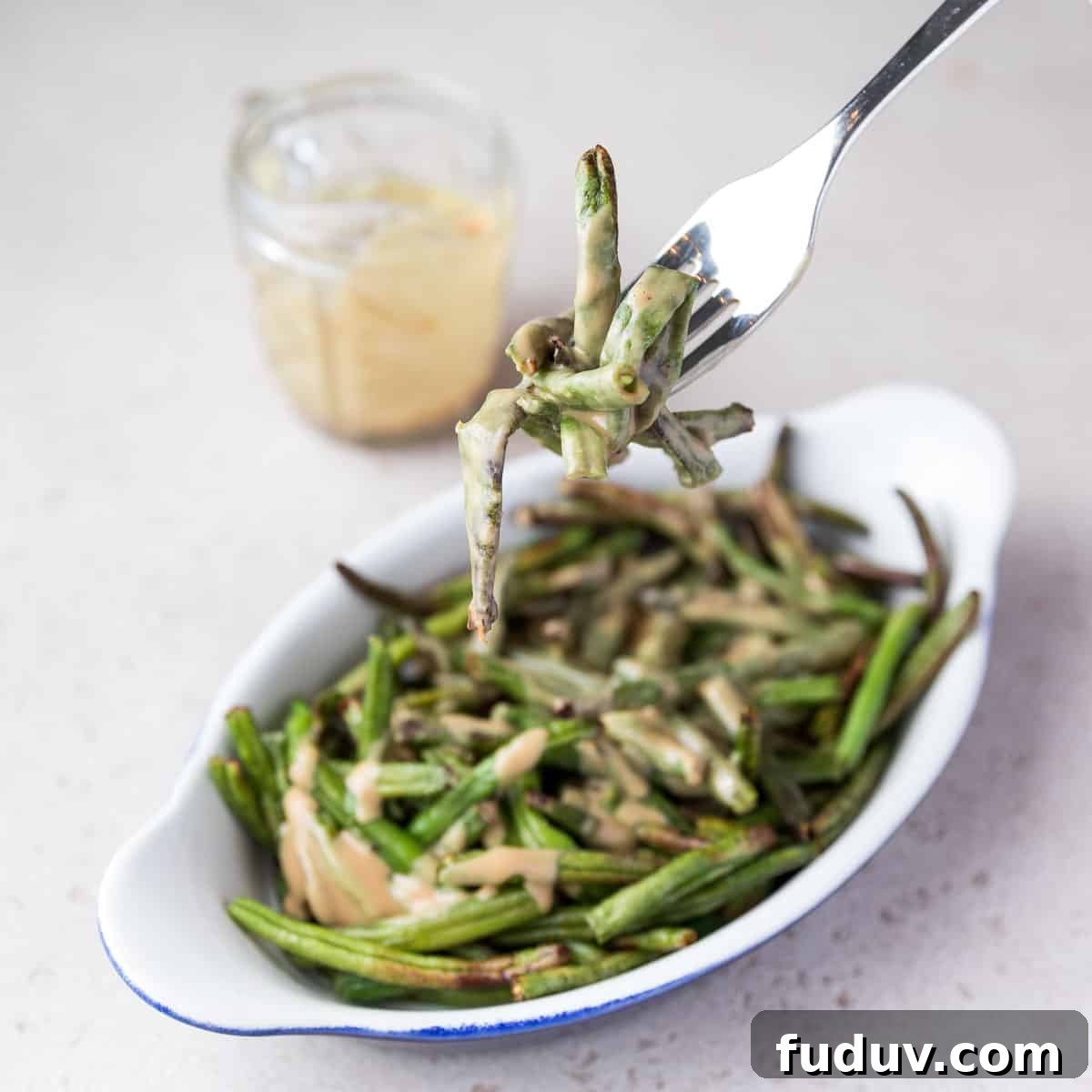 Crispy Air-Fried Frozen Green Beans with Creamy Tahini Sauce 14 Photo showing someone taking a forkful of air fried frozen green beans.