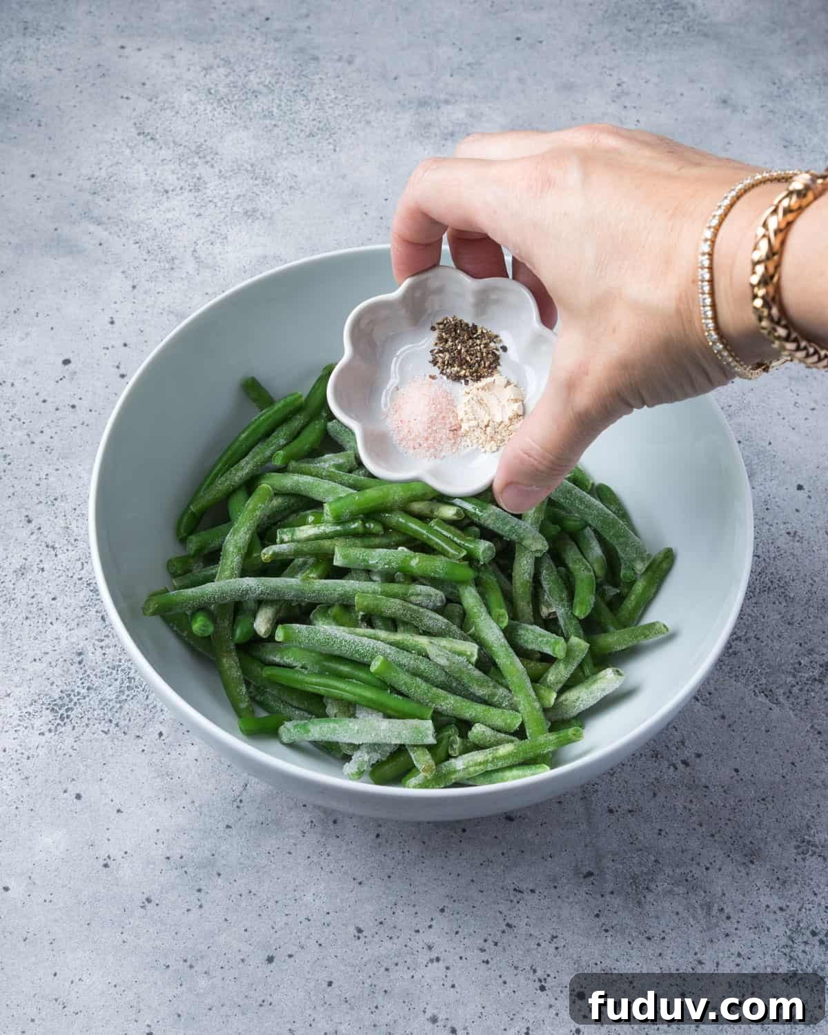 Crispy Air-Fried Frozen Green Beans with Creamy Tahini Sauce 8 Photo showing seasoning being added to the bowl of frozen green beans.