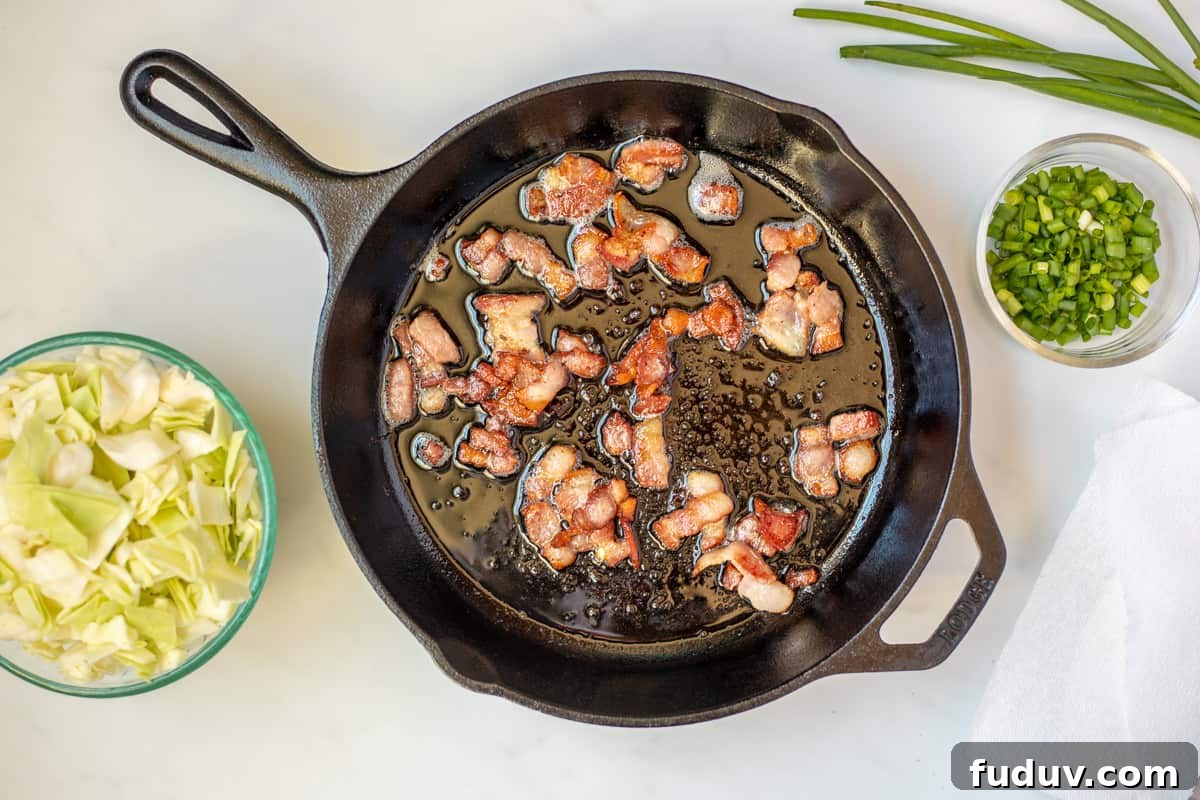 Bacon in skillet after browning with cabbage on the side.