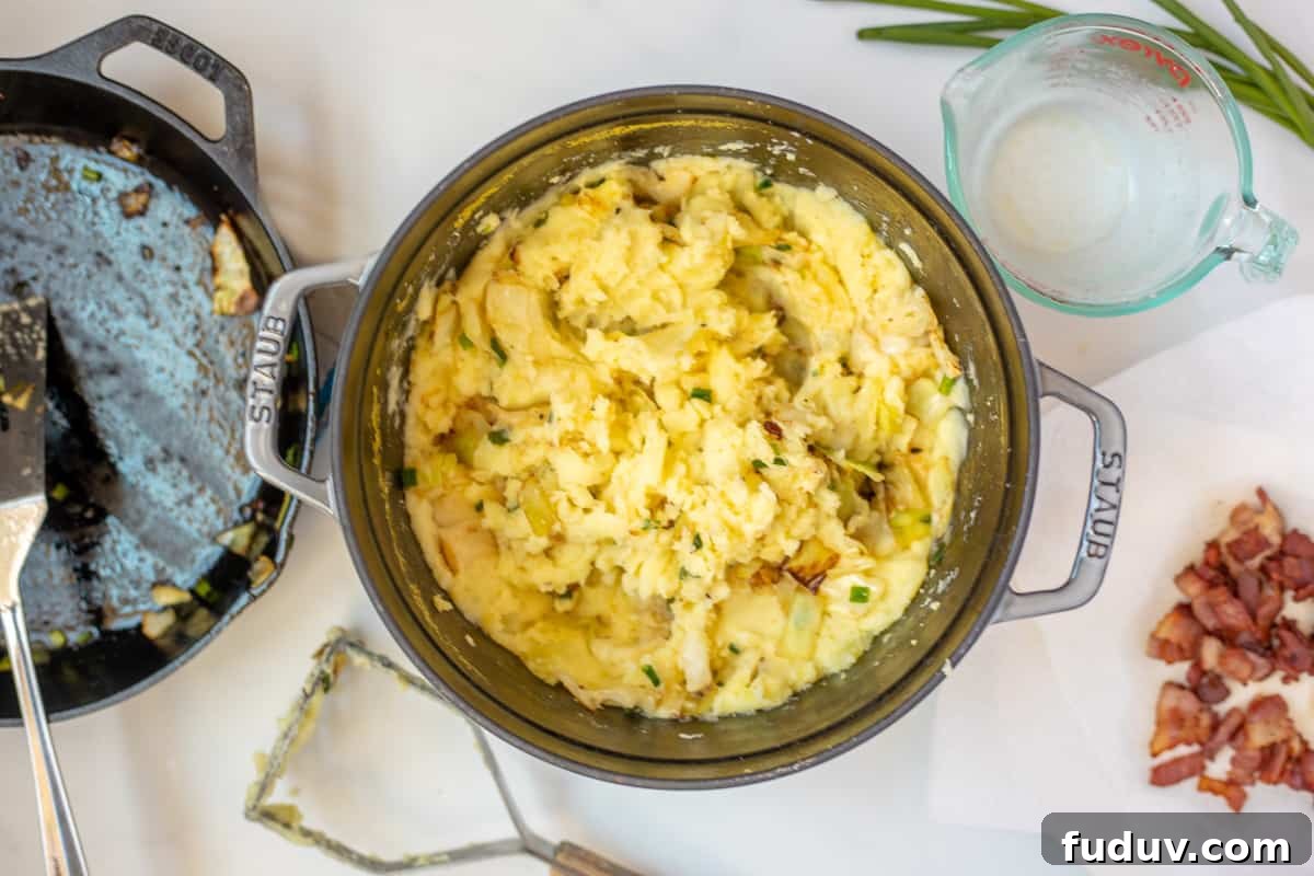Mashed Potatoes mixed with cabbage and bacon inside dutch oven skillet.