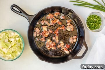 Bacon in skillet after browning with cabbage on the side.