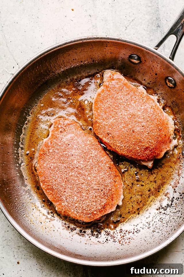 Juicy, tender, and flavorful, these garlic parmesan pan fried pork chops are smothered in a rich honey garlic sauce. Done in just 20 minutes! Frying smothered pork chops in a skillet.
