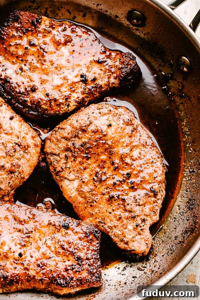 Juicy, tender, and flavorful, these garlic parmesan pan fried pork chops are smothered in a rich honey garlic sauce. Done in just 20 minutes! Pan fried pork chops in a skillet.