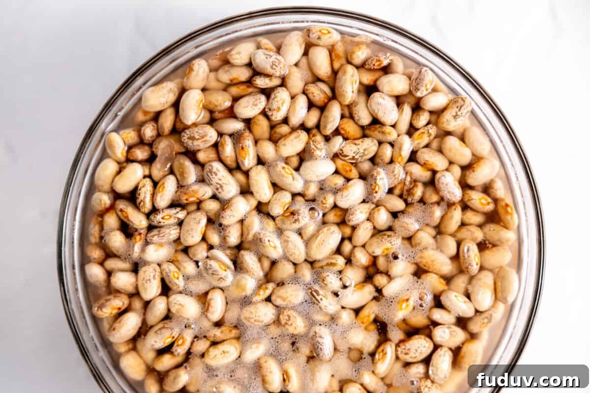 Pinto beans soaking in a bowl of water.