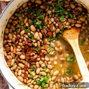 Pot of charro beans topped with cilantro and crispy bacon.