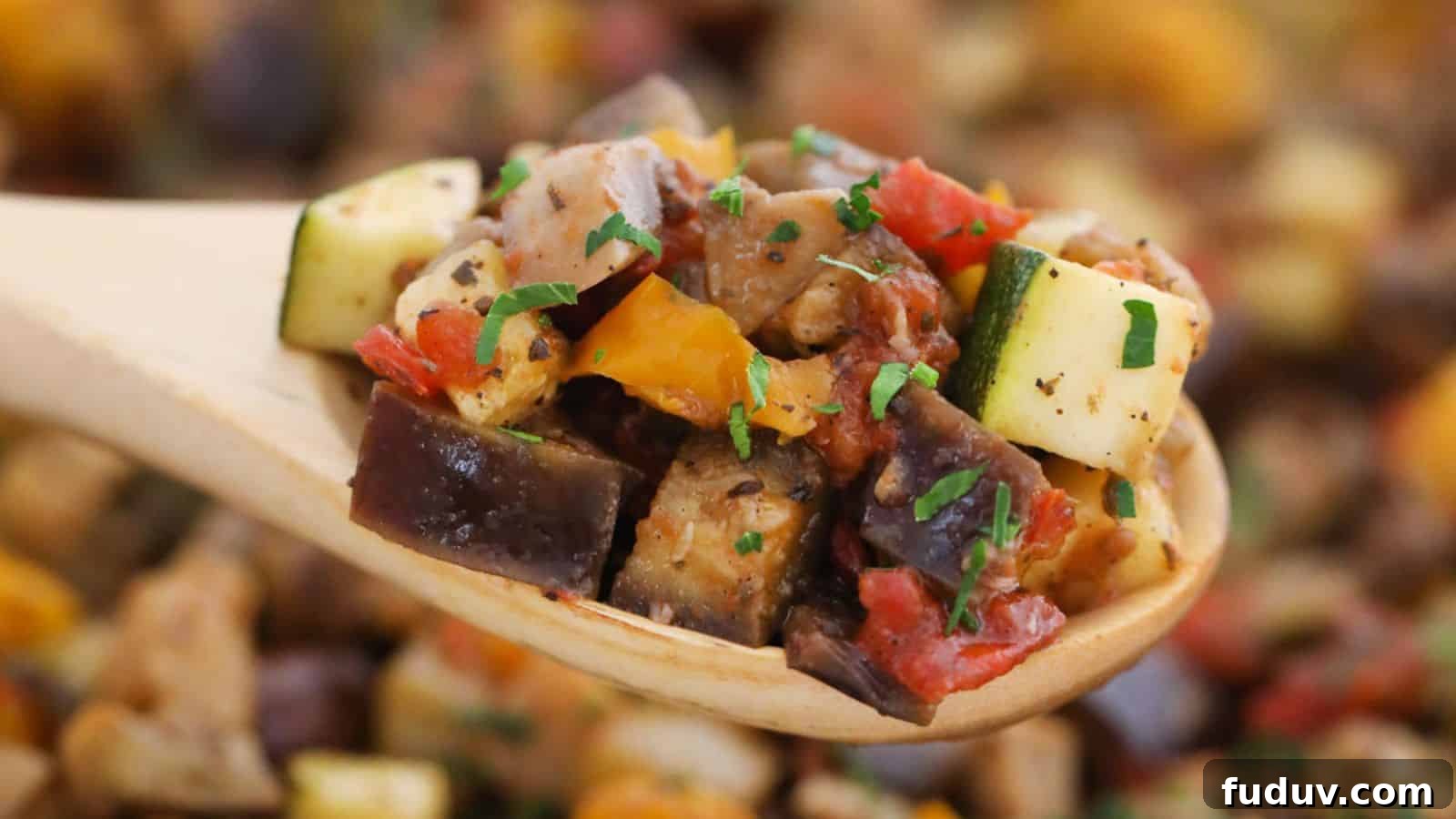 Close-up of a wooden spoon holding ratatouille, featuring diced zucchini, eggplant, and tomatoes, garnished with parsley.