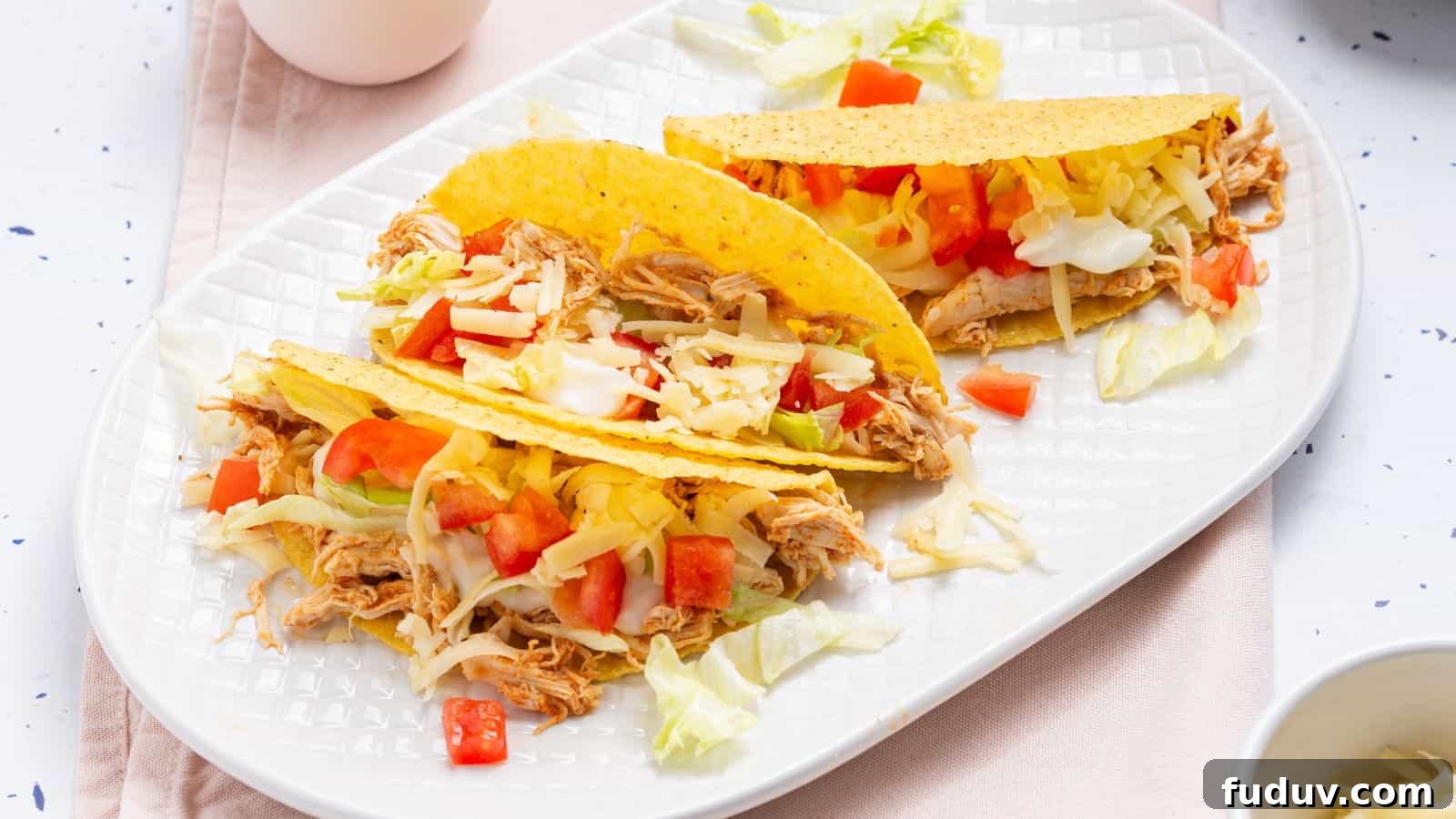 Two tacos on a plate with a bowl of guacamole.