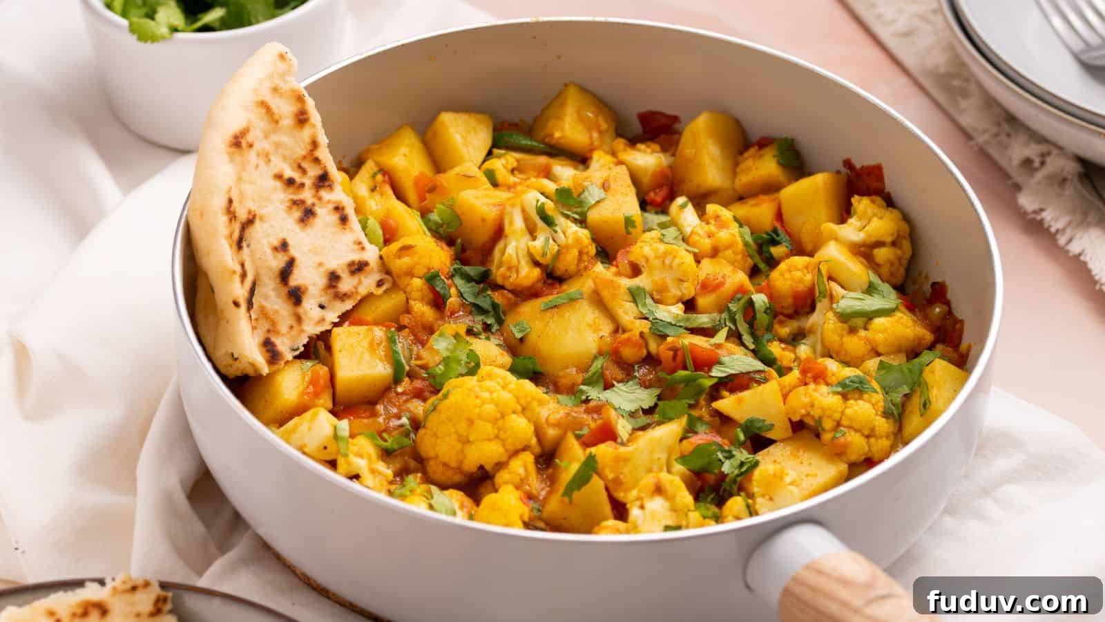 Aloo gobi masala in skillet with naan bread.