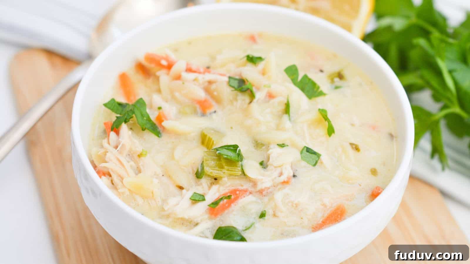 Lemon chicken soup in a white bowl with lemon slices.