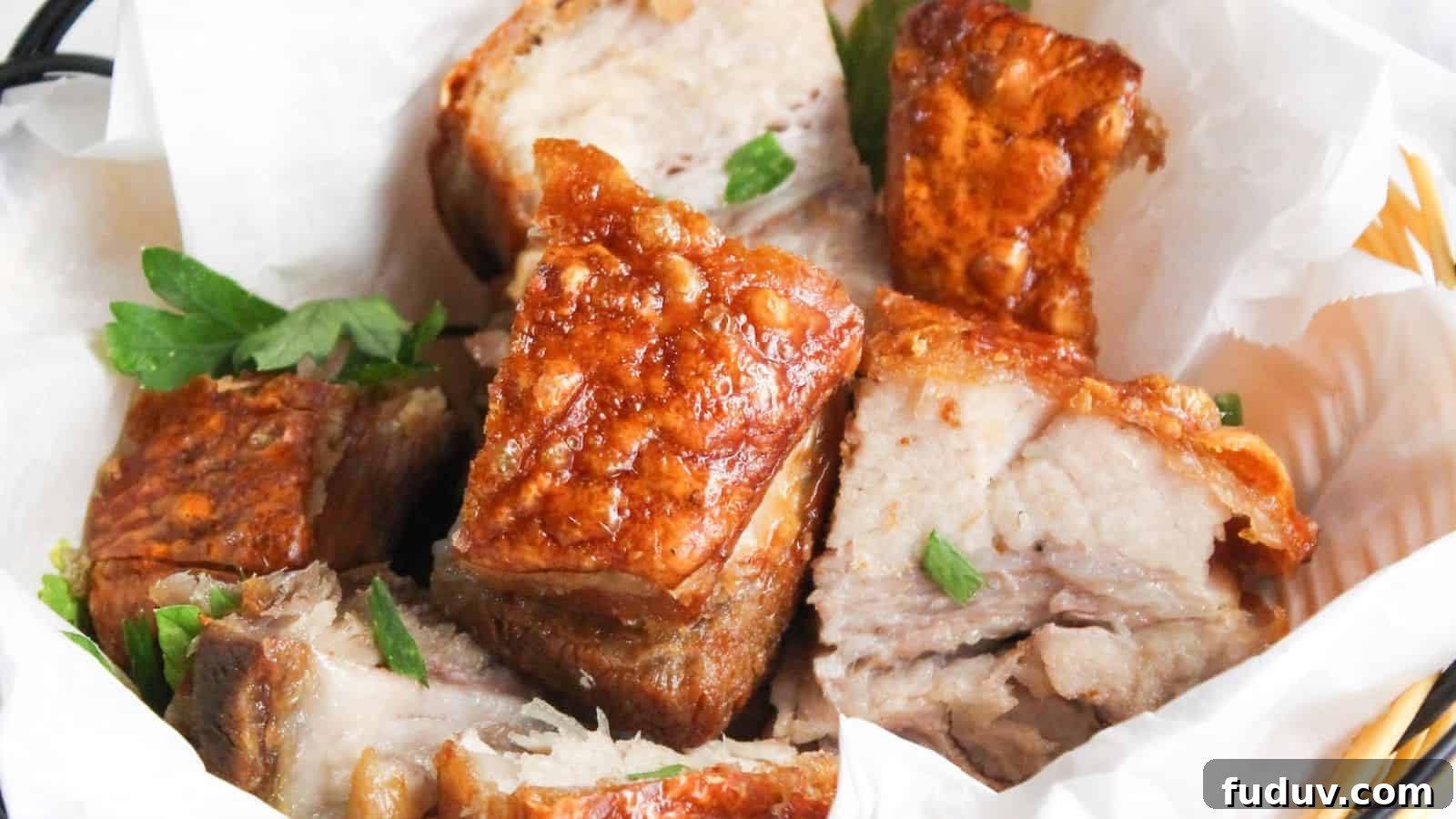 A basket of crispy roasted pork belly chunks garnished with parsley, served in a white paper-lined wicker basket.