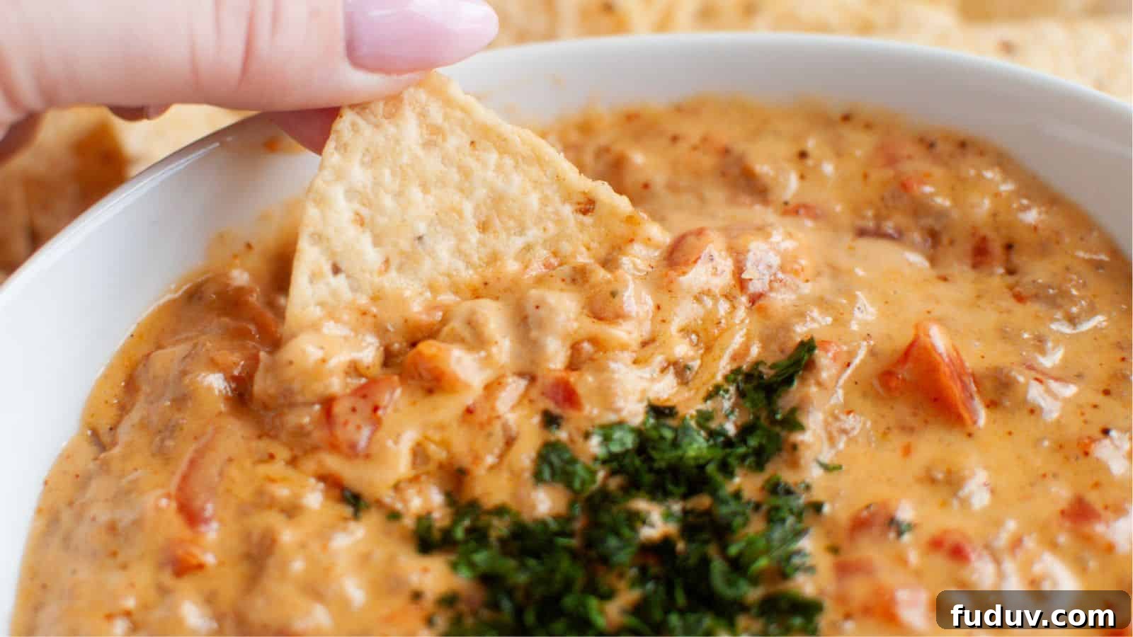 A bowl of beef queso dip with a spider web on top served with celery sticks.
