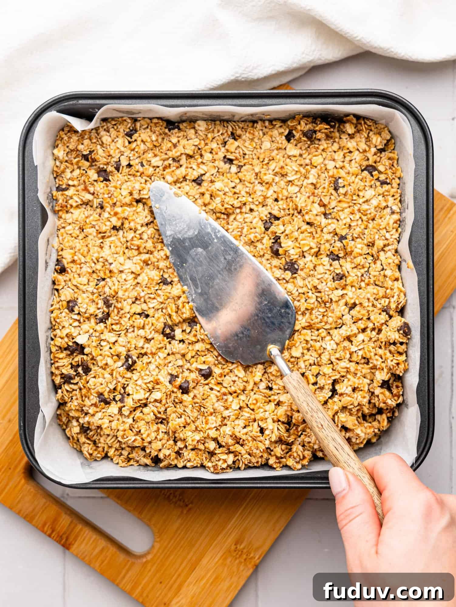 Pressing the flapjack mixture into a baking tin with a cake slice.