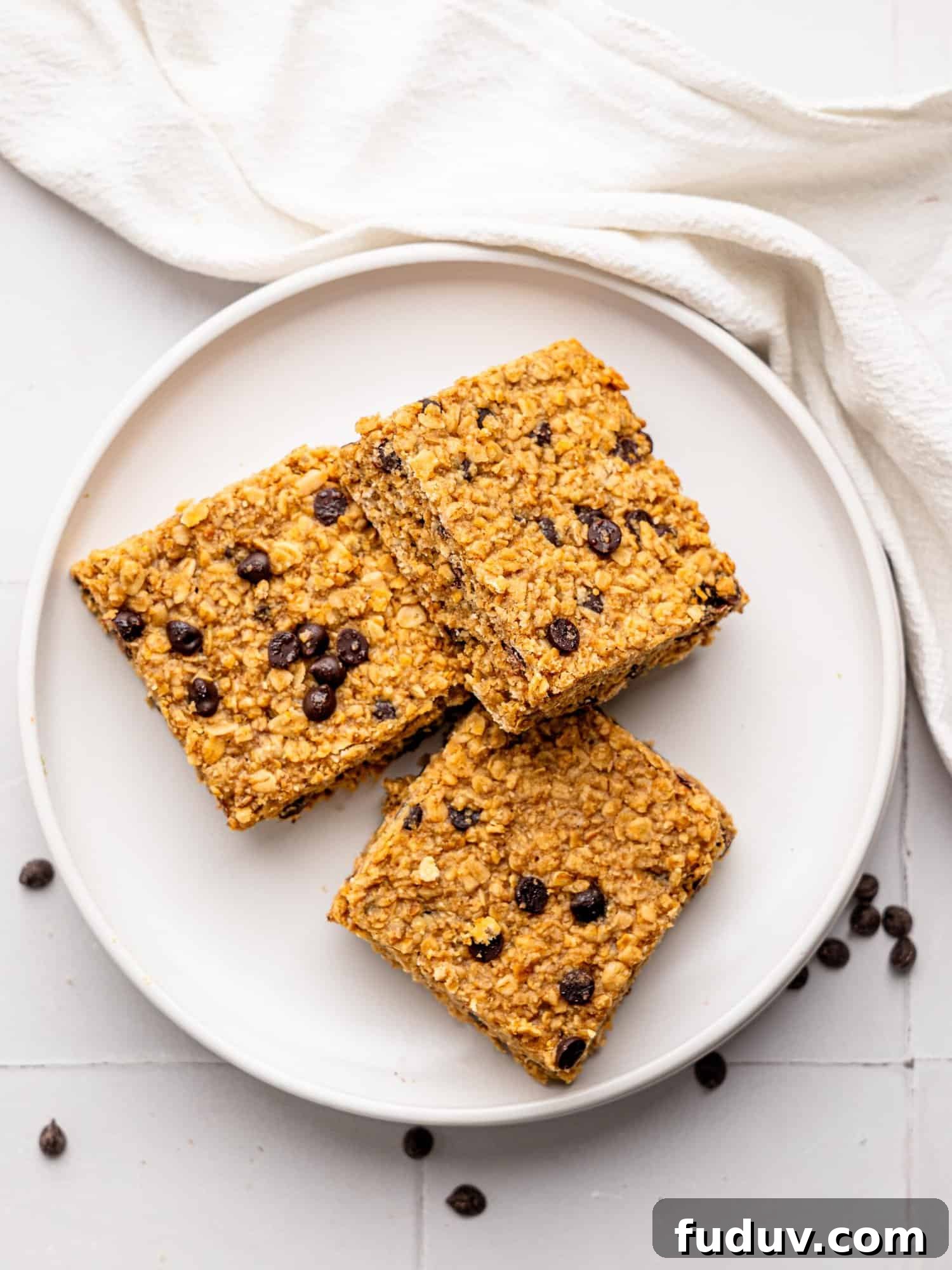 Bird's eye view of three chocolate chip flapjacks on a white plate.