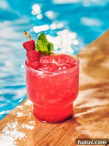 Raspberry Mule in a glass topped with mint and fresh raspberries, by a pool.