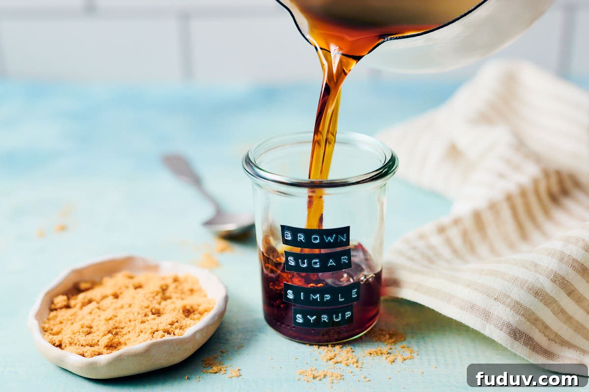 Brown rice simple syrup being poured into a glass jar on a kitchen counter.
