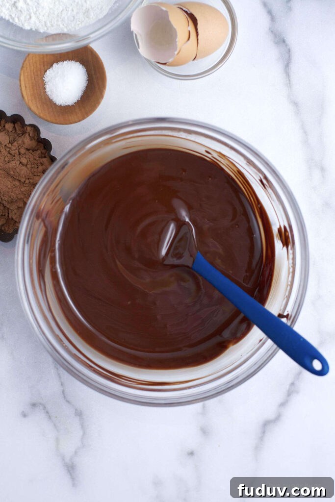 Chewy Brownie Crinkle Cookies Recipe for Fudgy Chocolate Lovers 7 melted butter and chocolate in a bowl with a spatula