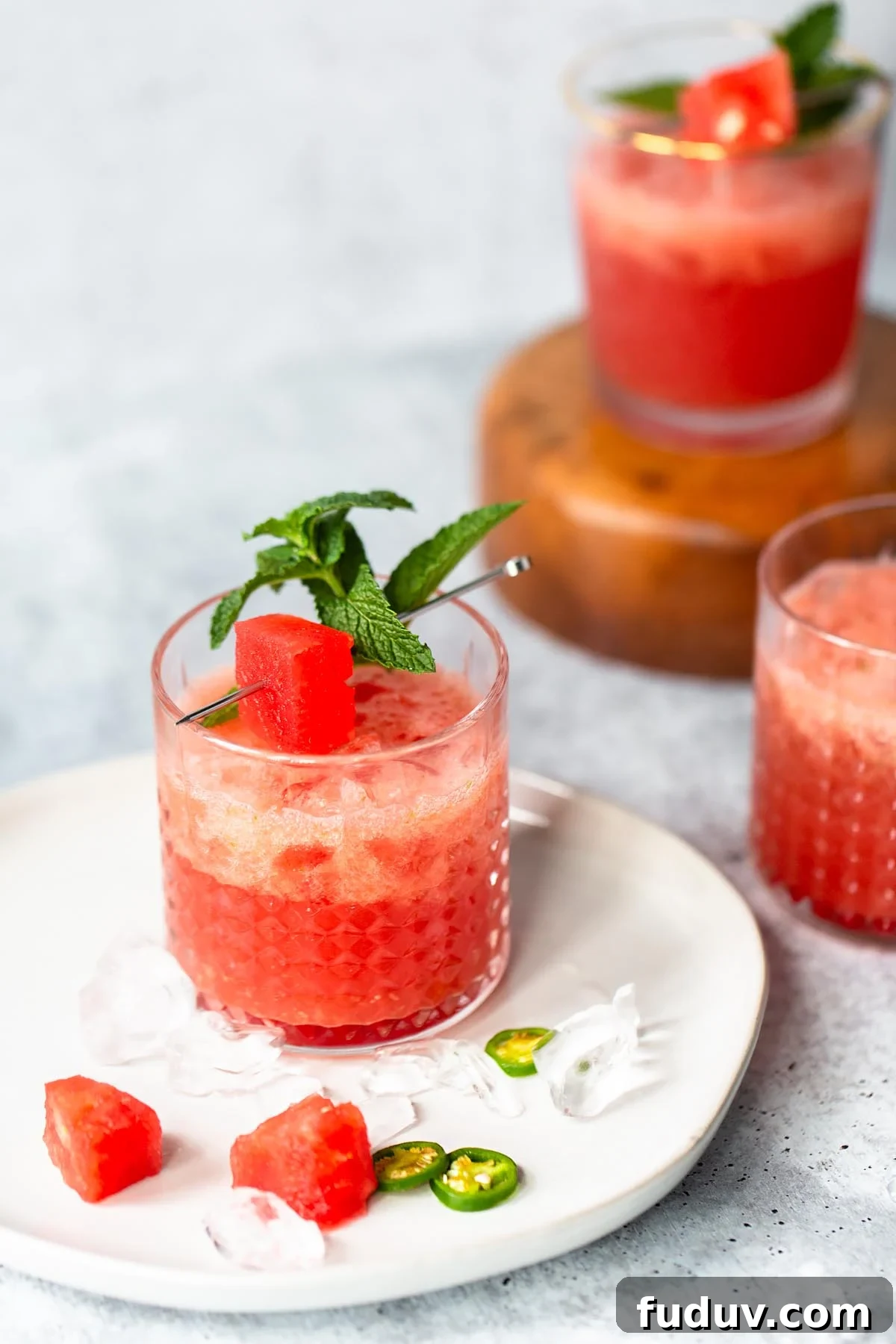 watermelon jalapeno drink on a plate with a watermelon and mint garlnish