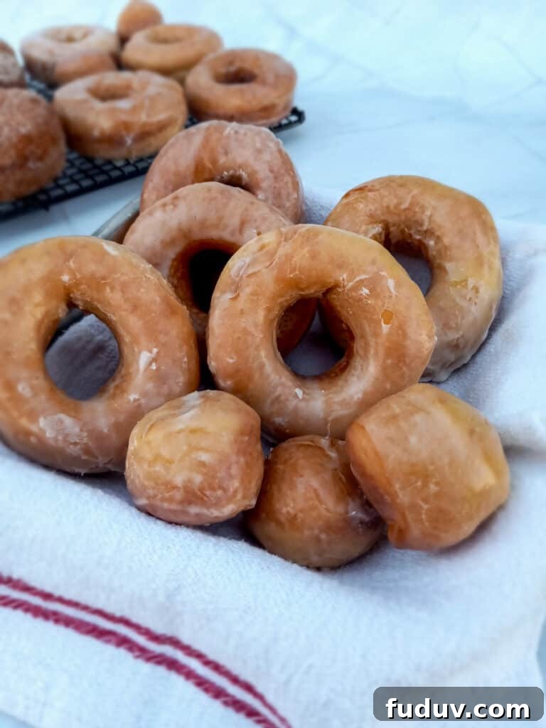 Amish glazed donuts sitting in a pan and some on a wire rack.