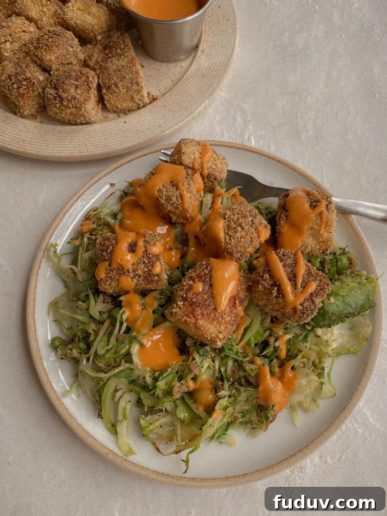 Crispy Baked Gluten-Free Tofu Nuggets: Crunchy Oven Recipe 2 crispy baked tofu on shaved brussels sprouts with drizzle of buffalo sauce on white plate with fork
