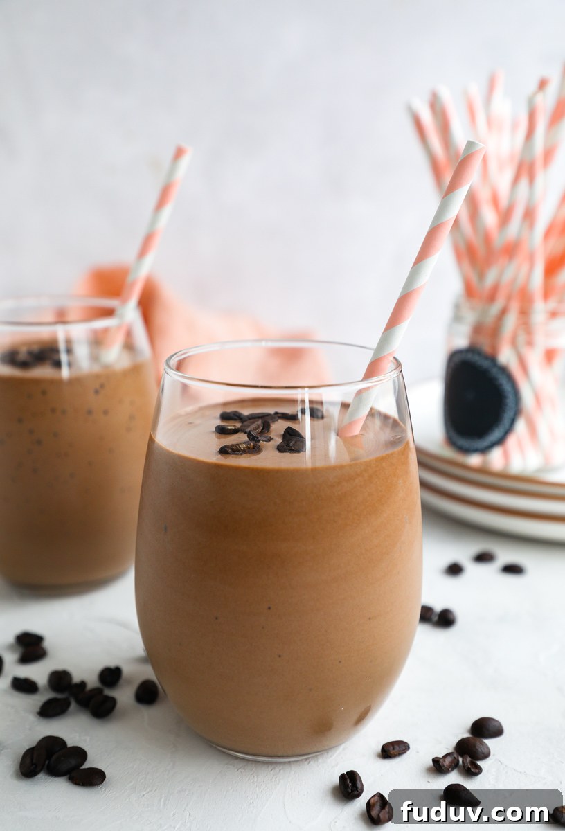 Creamy Mocha Protein Smoothie Recipe for Energy and Muscle Recovery 5 2 coffee smoothies in stemless wine glasses surrounded by pink paper straws and coffee beans