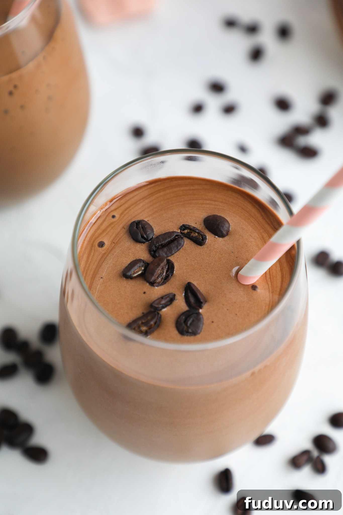 Creamy Mocha Protein Smoothie Recipe for Energy and Muscle Recovery 7 A thick mocha protein smoothie poured into a wine glass topped with coffee beans and a pink straw