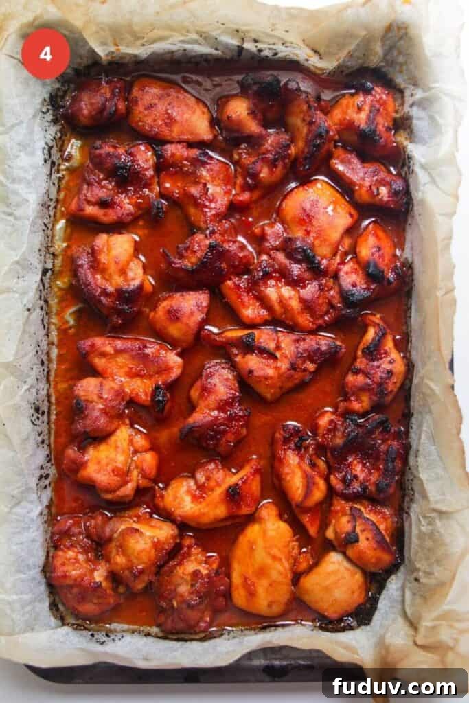 Sticky Gochujang Chicken Recipe: Sweet Spicy Korean Glaze 7 Cooked, charred gochujang chicken on oven tray.