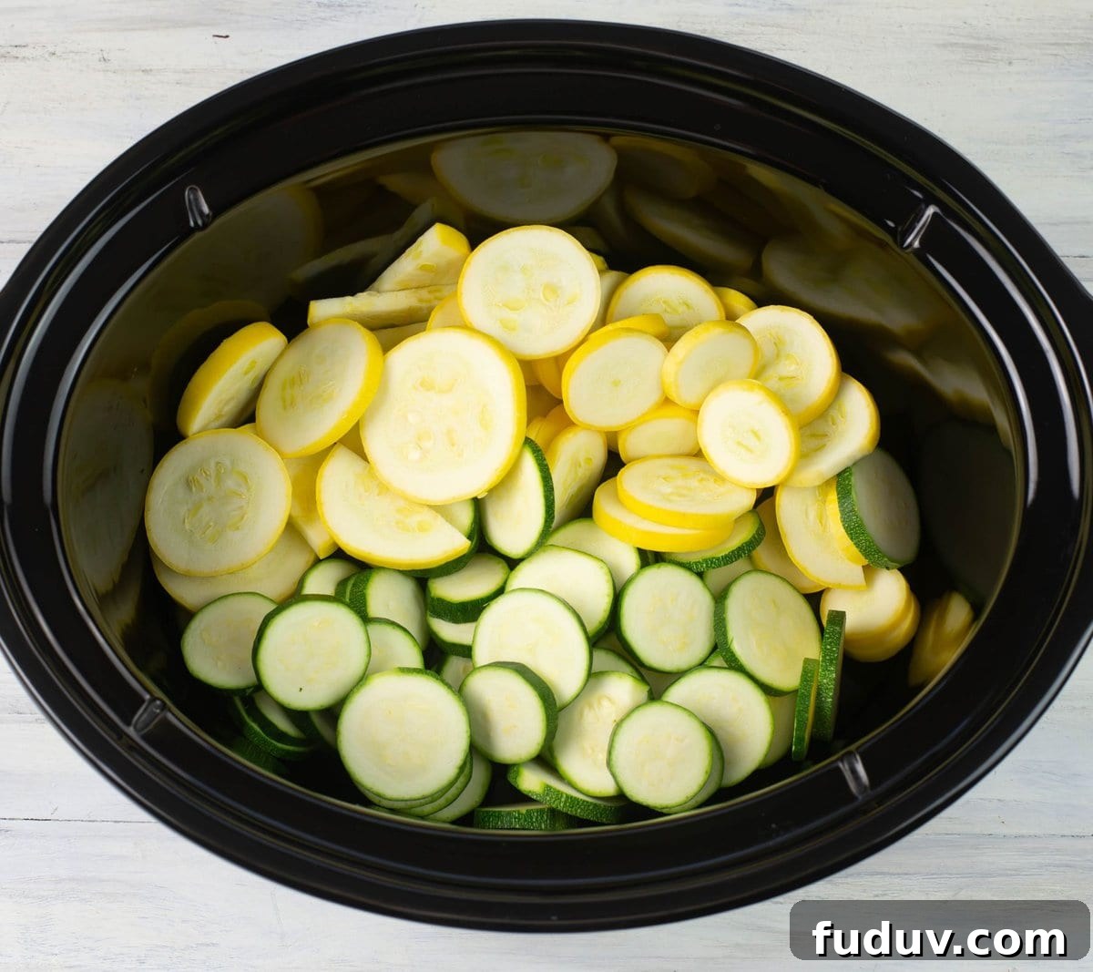 Sliced yellow squash and green zucchini in the crock pot. 