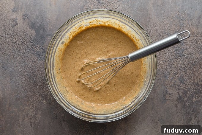 Cake batter being whisked together in a glass bowl.