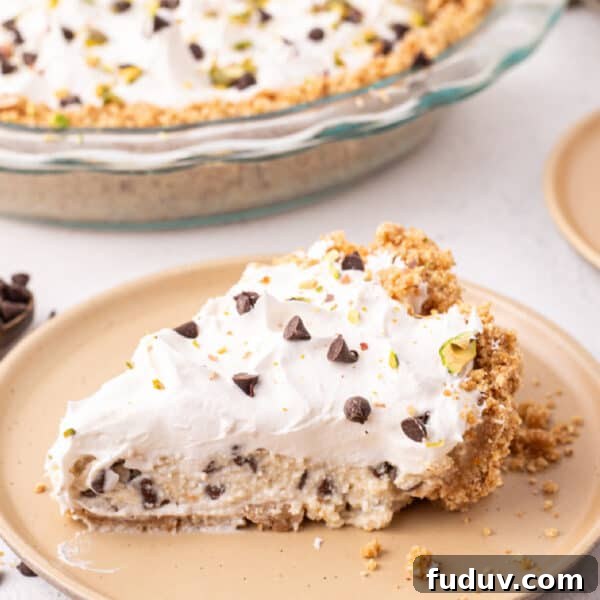 slice of no bake cannoli pie with whipped topping, chocolate chips, and pistachios