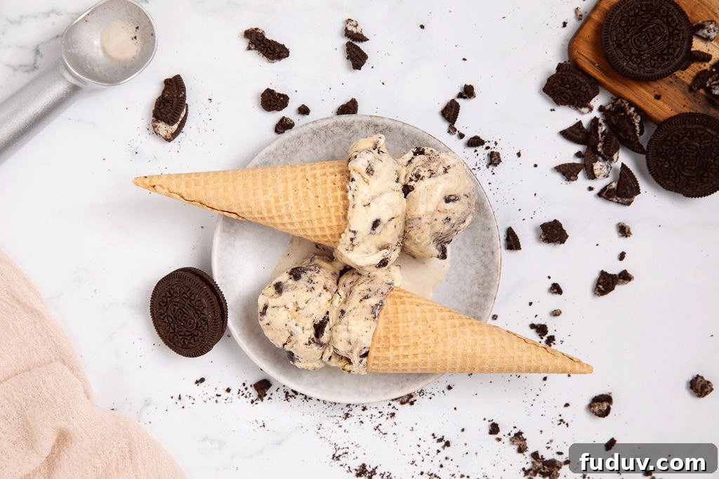Two ice cream cones with cookies and cream ice cream in them.
