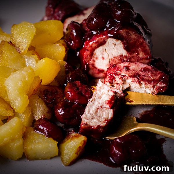 A plate of roast pork with red wine cherry sauce with crispy sautéed potatoes.