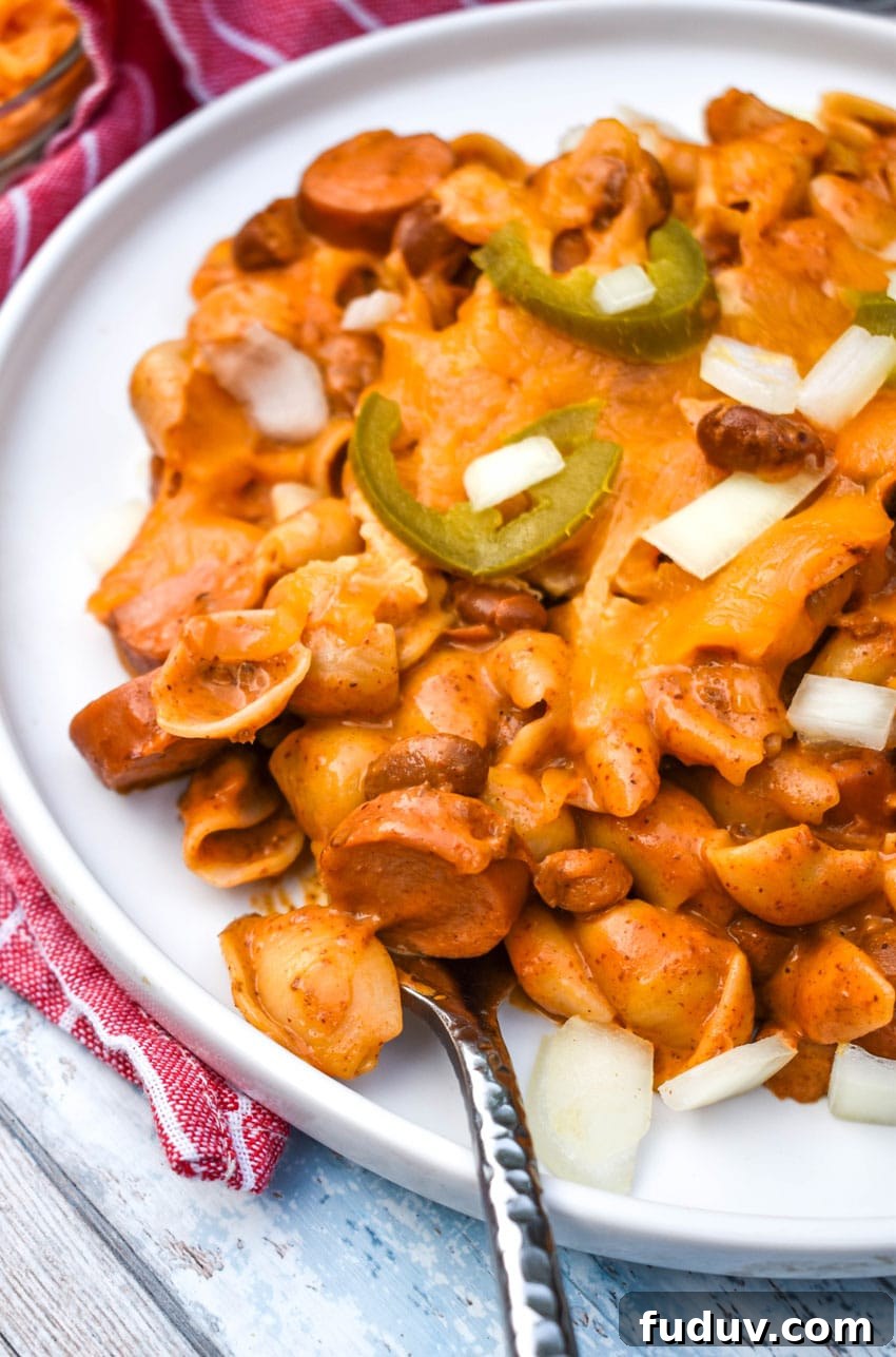 Chili Dog Mac & Cheese from a Box — Quick Classic Recipe 7 chili dog mac and cheese with hot dogs on a white plate with two silver forks on the side
