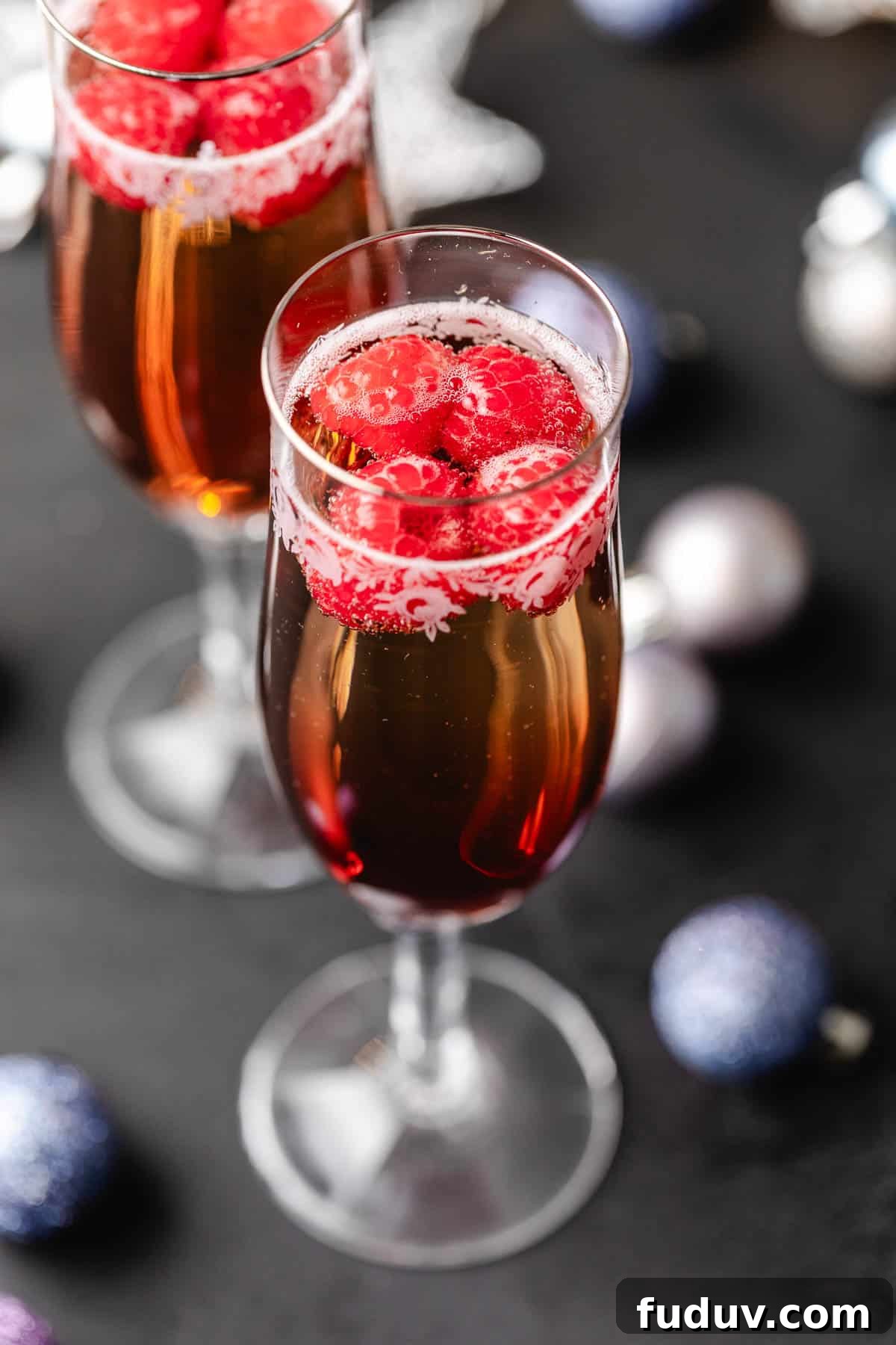 How to Make a Chambord and Prosecco Cocktail (Raspberry Fizz) 3 Top down view of raspberries floating in a glass of chambord and champagne.