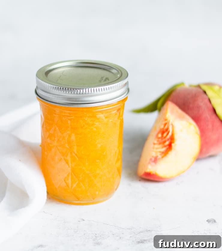 Small-Batch Bourbon Peach Jam Recipe for Preserving Summer Flavor 5 jar of peach jam with peaches next to it