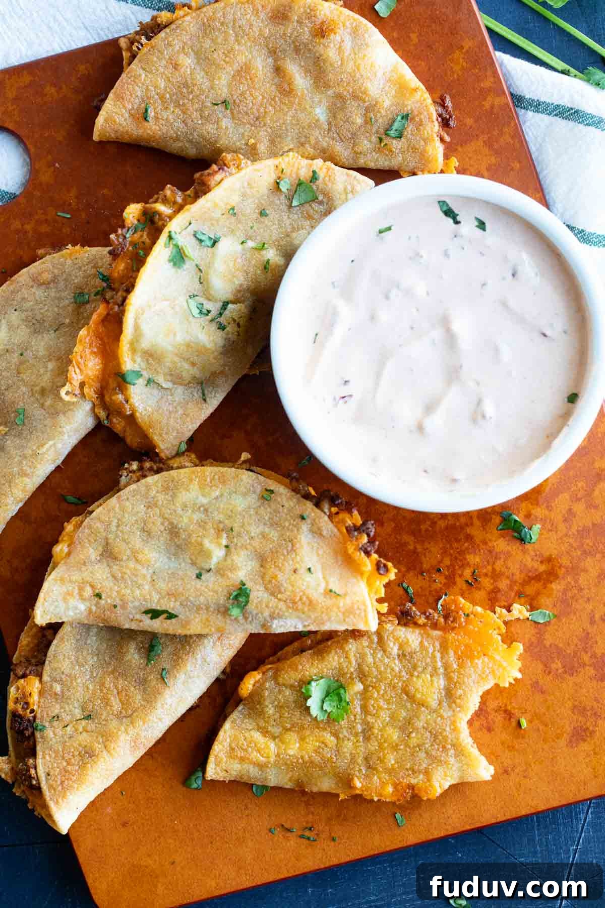 Crispy Chicken Tacos with Tangy Slaw and Avocado crema 7 Crispy Chicken Tacos on a cutting board with a bite taken from one taco.