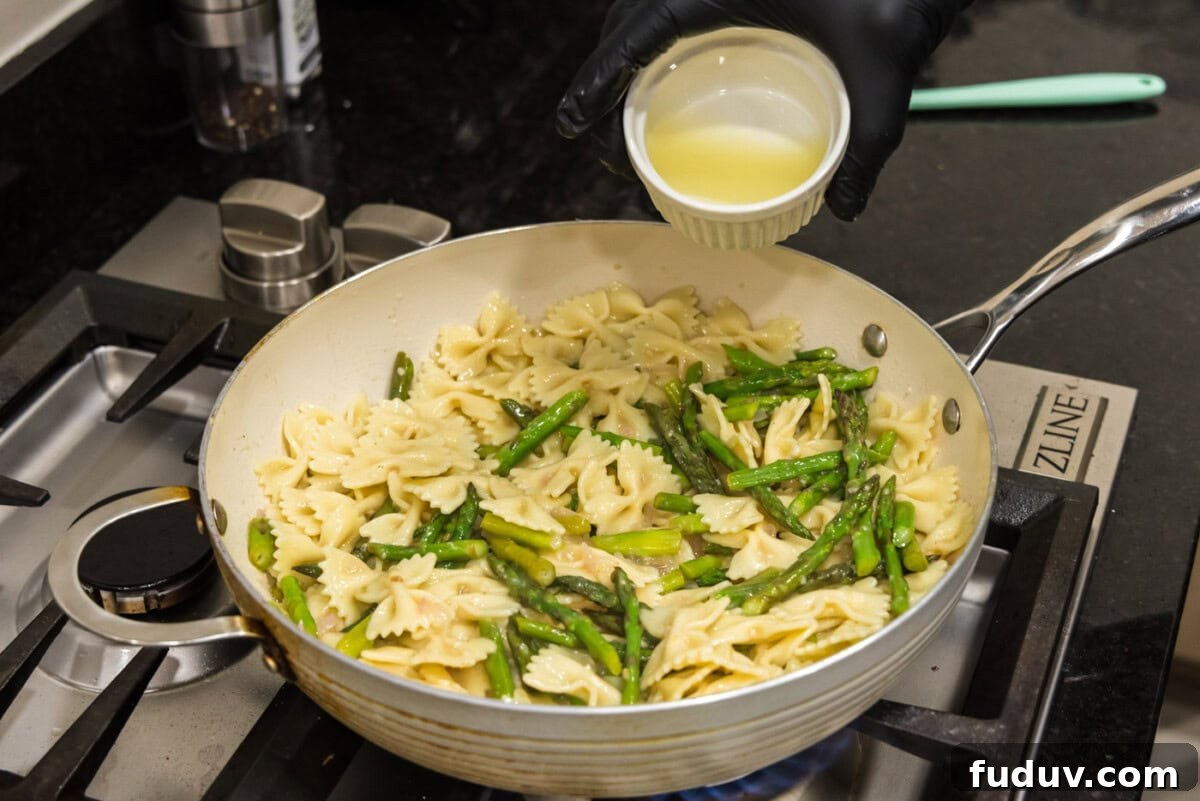 pouring lemon juice over asparagus pasta