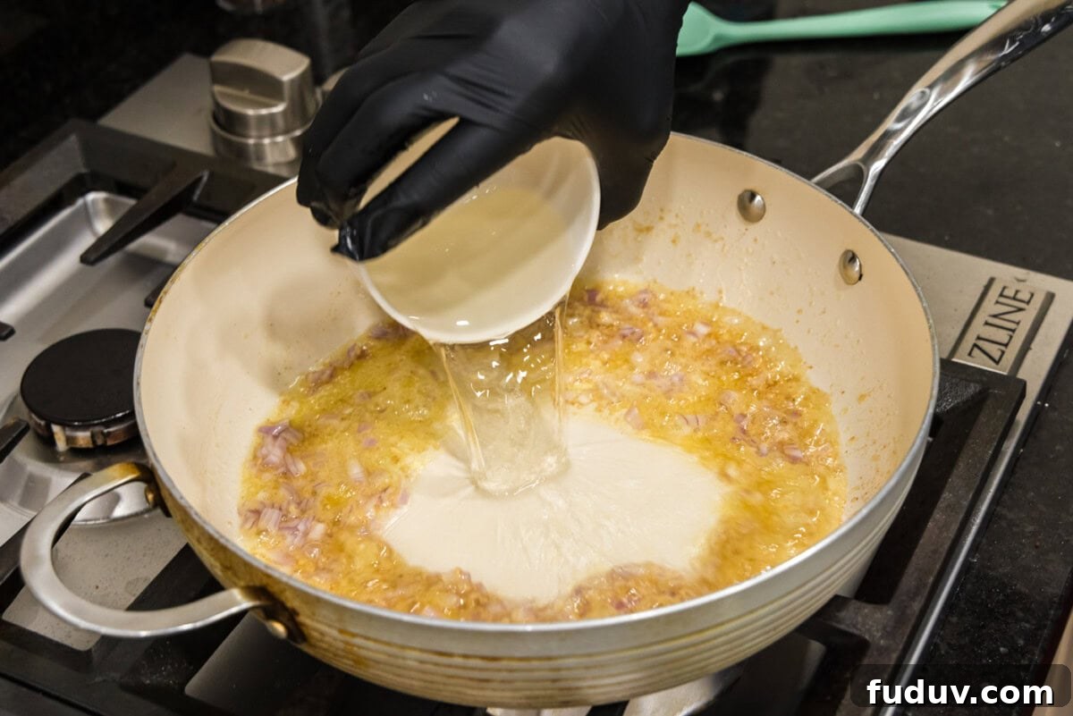 pouring white wine into skillet with butter and shallots